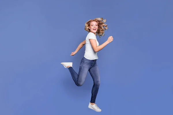 Longitud completa tamaño del cuerpo vista de la encantadora alegre chica de pelo ondulado saltando corriendo aislado sobre fondo de color azul — Foto de Stock