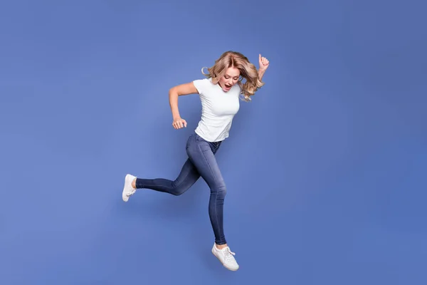 Foto lateral de perfil de longitud completa de mujer joven feliz sorprendido ir caminar salto mirada espacio vacío aislado sobre fondo de color azul — Foto de Stock