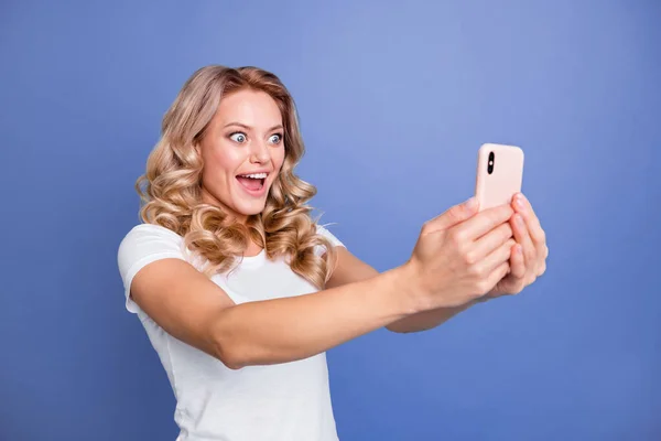Портрет привабливої здивованої веселою хвилястою дівчинкою з використанням гаджета швидкого wi-fi роумінгу веб ізольовано на синьому кольоровому фоні — стокове фото