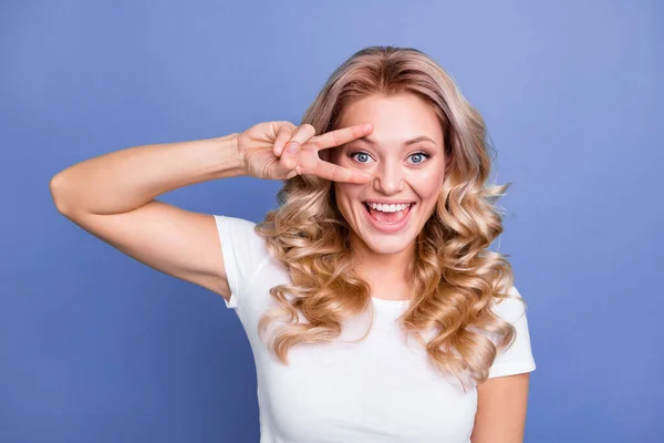 Foto di giovane bella attraente bella sorridente ragazza eccitata mostrando v-segno su occhio isolato su sfondo di colore blu — Foto Stock