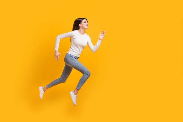 Full size profile photo of optimistic nice girl jump run wear sweater jeans sneakers isolated on yellow color background — Stock Photo, Image