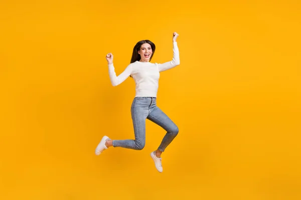 Foto em tamanho completo de hooray menina salto desgaste camisola jeans tênis isolado no fundo de cor amarela — Fotografia de Stock