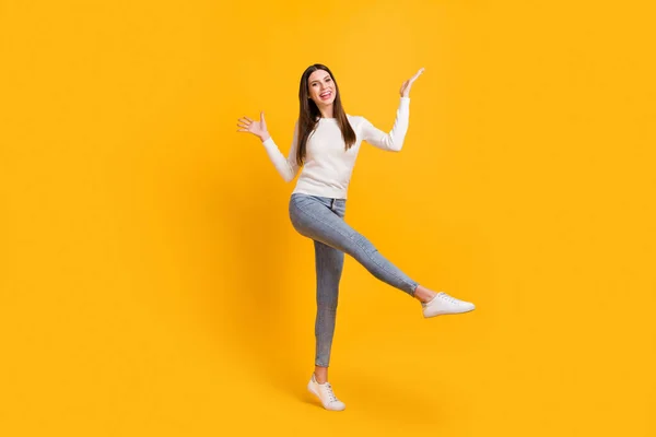 Full size φωτογραφία του αισιόδοξου μελαχρινή κορίτσι χορού φορούν πουλόβερ τζιν αθλητικά παπούτσια απομονωμένα σε κίτρινο χρώμα φόντο — Φωτογραφία Αρχείου
