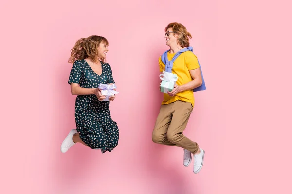 Volledige grootte profiel foto van optimistisch grappig paar springen hold huidige dragen kleurrijke kleren geïsoleerd op pastel roze achtergrond — Stockfoto