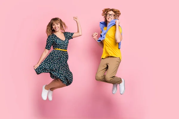 Teljes méretű fotó optimista vicces pár ugrás viselni színes ruhák elszigetelt pasztell rózsaszín háttér — Stock Fotó