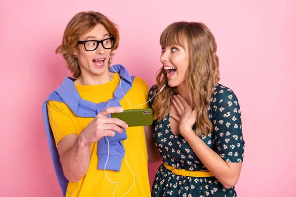 Foto di impressionato bella coppia guardare video indossare vestiti colorati isolati su sfondo rosa pastello — Foto Stock