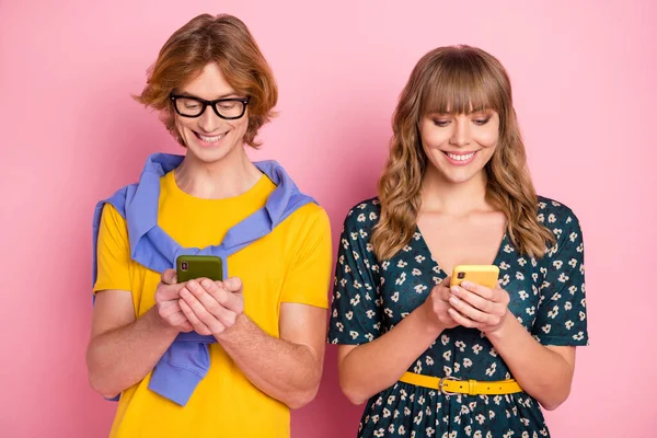 Foto di ottimista bella coppia sguardo telefono indossare vestiti colorati isolati su sfondo rosa pastello — Foto Stock