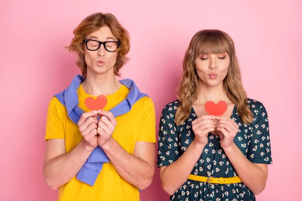 Foto retrato de casal com lábios despojados mantendo símbolo de amor coração vermelho isolado no fundo cor-de-rosa pastel — Fotografia de Stock