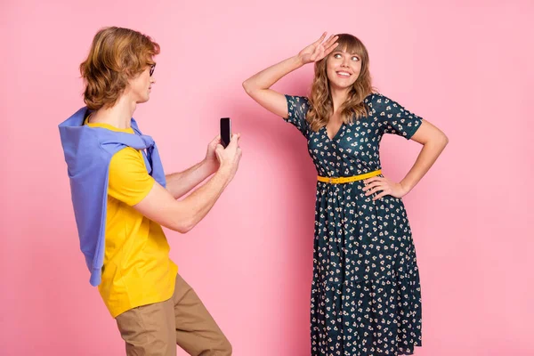 Foto de jovem namorado engraçado funky tirar foto no telefone de sua namorada sorridente isolado no fundo cor-de-rosa — Fotografia de Stock