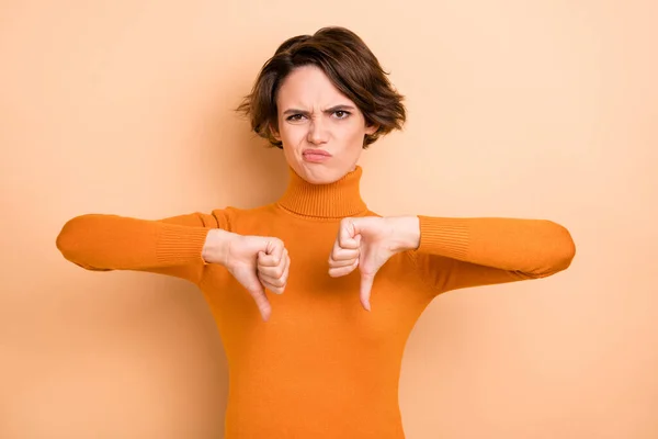 Photo of charming sad young lady wear orange turtleneck showing thumbs down two hands arms isolated beige color background — Stock Photo, Image