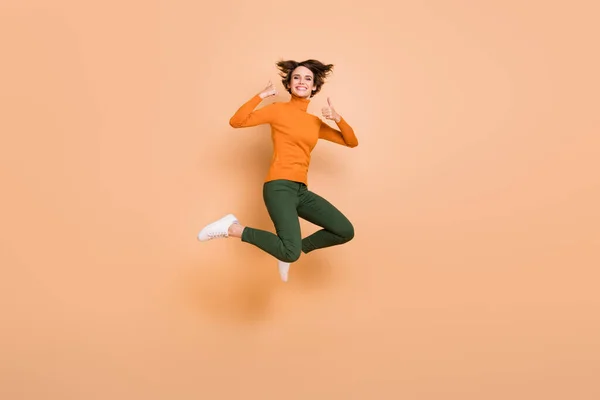 Teljes méretű fotó fiatal boldog izgatott pozitív vidám lány jumping bemutató hüvelykujj-up elszigetelt bézs színű háttér — Stock Fotó