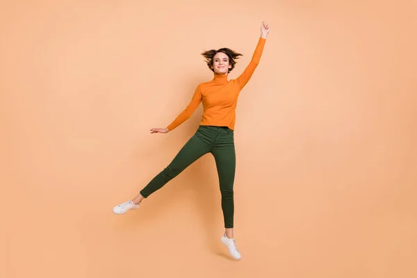 Lunghezza completa foto di cute lucido giovane signora indossare arancione dolcevita salto cattura isolato colore beige sfondo — Foto Stock