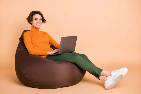 Foto ukuran penuh gadis muda yang cantik dengan senyum yang ceria gadis mood duduk tipe kursi berlengan di laptop terisolasi dengan latar belakang warna krem — Stok Foto