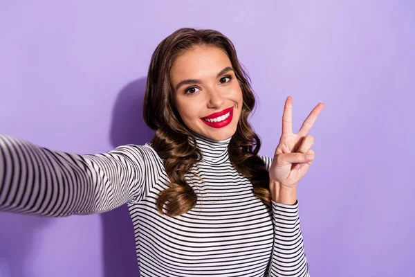 Foto de bonito doce jovem usar roupa listrada mostrando v-sinal de gravação de vídeo isolado cor violeta fundo — Fotografia de Stock