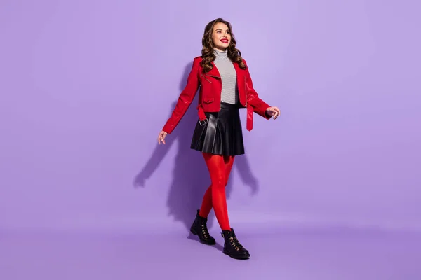 Фото очаровательной милой молодой женщины носить красный наряд ходьба выглядит пустое пространство изолированный фиолетовый цвет фона — стоковое фото