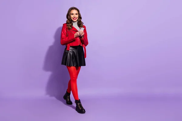 Foto von niedlichen hübschen jungen Frau tragen rotes Outfit zu Fuß Eingabe moderner Gerät leeren Raum isoliert violette Farbe Hintergrund — Stockfoto