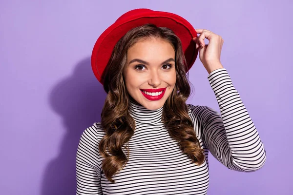 Foto de dulce encantadora dama joven vestida a rayas brazo gorra sonriente aislado color púrpura fondo — Foto de Stock