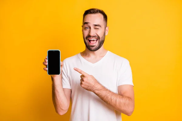 Portret van aantrekkelijke vrolijke man houden in de hand demonstreren apparaat knipperen geïsoleerd over helder gele kleur achtergrond — Stockfoto