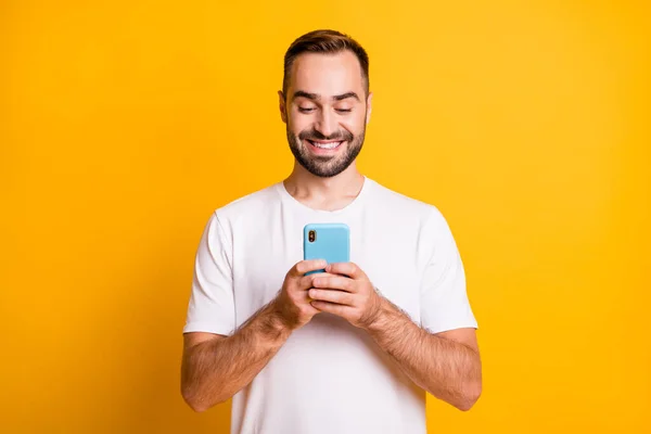 Retrato de otimista cara segurar telefone desgaste branco t-shirt isolado no vibrante amarelo cor de fundo — Fotografia de Stock