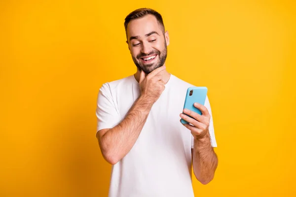 Retrato de cara otimista olhar telefone desgaste branco t-shirt isolado na cor amarela vibrante fundo — Fotografia de Stock