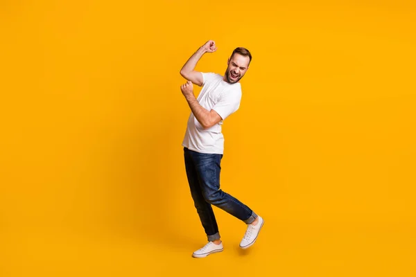 Foto de perfil de tamaño completo de hombre optimista danza cantar desgaste gris camiseta jeans zapatillas aisladas sobre fondo de color amarillo — Foto de Stock