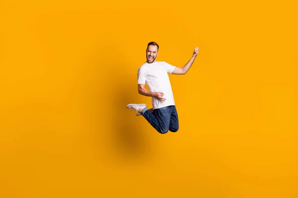 Pełna długość ciała rozmiar widok ładny ekstatyczny wesoły facet skacze grając niewidzialną gitarę izolowane nad jasnożółty kolor tła — Zdjęcie stockowe