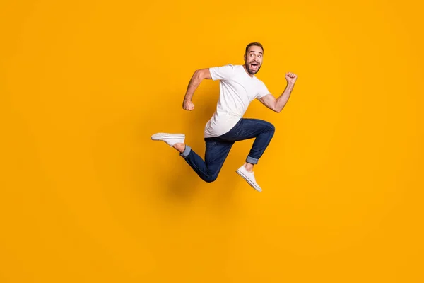 Фотография бокового профиля полного размера тела прыгающего человека, бегущего быстро изолированный яркий желтый фон — стоковое фото