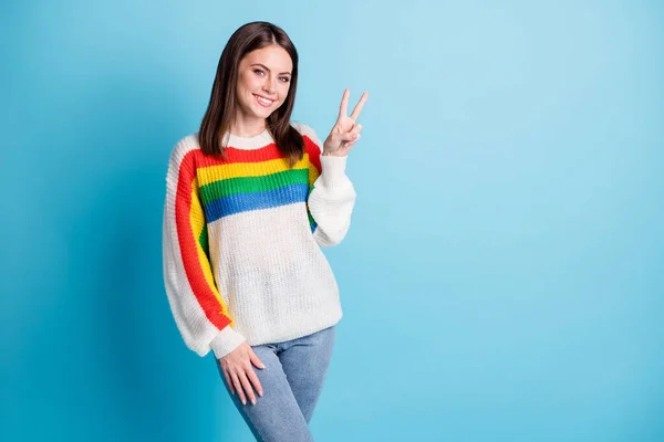 Foto de criança adorável jovem senhora desgaste colorido pulôver sorrindo mostrando v-sinal vazio espaço isolado azul cor fundo — Fotografia de Stock