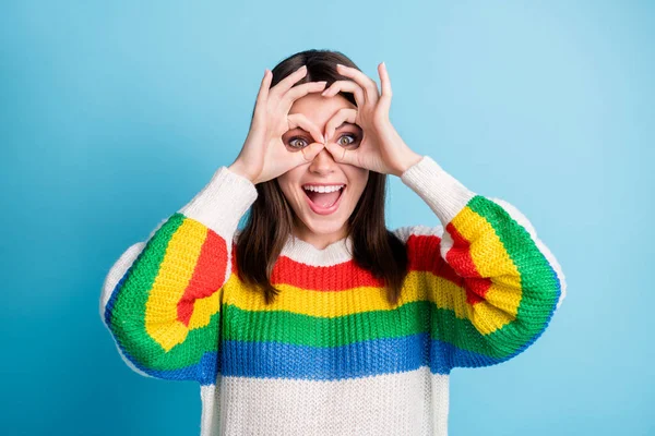 Foto van schattige speelse jonge dame dragen kleurrijke trui glimlachen tonen vingers bril geïsoleerde blauwe kleur achtergrond — Stockfoto