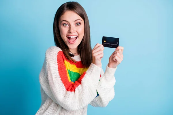 Bild av charmiga imponerad ung dam bära färgglada pullover innehav kreditkort tomt utrymme isolerad blå färg bakgrund — Stockfoto