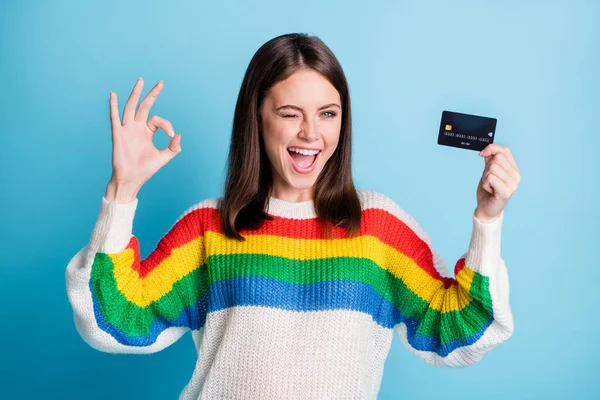 Photo of optimistic nice brunette lady show card okey blink wear sweater isolated on blue color background — Stock Photo, Image