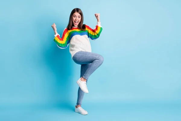 Foto de longitud completa de adorable mujer joven afortunada vestido suéter a rayas levantando puños espacio vacío aislado fondo de color azul — Foto de Stock