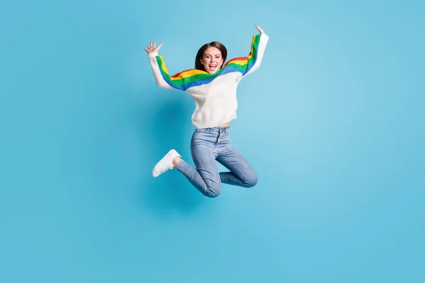 Foto de longitud completa de la encantadora joven excitada usar colorido jersey saltando brazos de gran altura aislado fondo de color azul — Foto de Stock