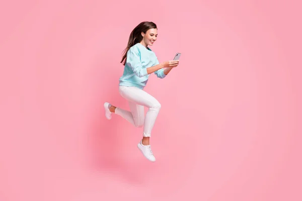 Full length profile photo of attractive blogger use phone in motion run fast write post isolated on pink color background — Stock Photo, Image