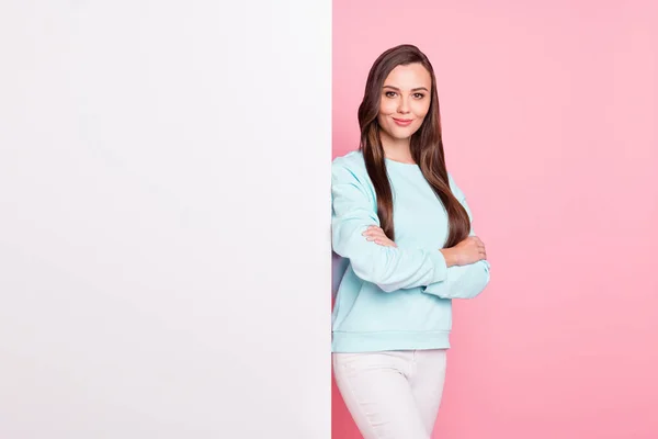 Foto de hermosa mujer de pelo castaño serio cruzó las manos de pie tablero en blanco espacio vacío aislado sobre fondo de color rosa pastel —  Fotos de Stock