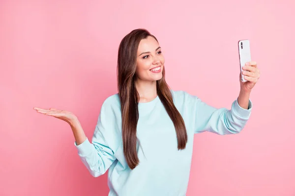 Foto de chica de cabello castaño sostener copyspace mano hacer selfie desgaste suéter azul aislado sobre fondo de color rosa — Foto de Stock