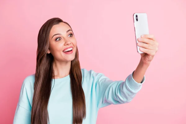 Фото привабливої красивої здивованої молодої жінки, що тримає телефон, знімають селфі ізольовано на пастельному блискучому рожевому фоні — стокове фото
