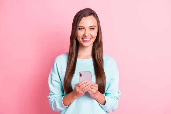 Zdjęcie uroczej uroczej dziewczyny ładny uśmiech trzymać smartfon dobry nastrój odizolowany na połysk różowy kolor tło — Zdjęcie stockowe