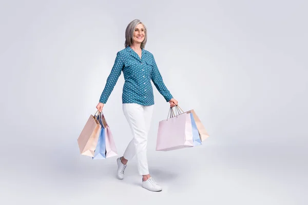 Longitud completa tamaño del cuerpo foto de la mujer mantener paquetes en compras sonriendo buscando espacio en blanco aislado sobre fondo de color blanco —  Fotos de Stock