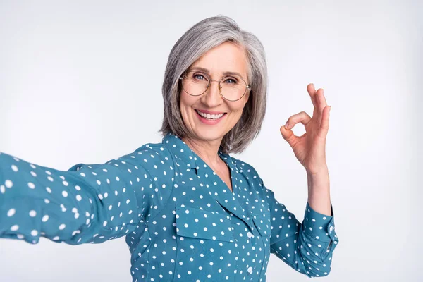 Auto-retrato de atraente alegre senhora de meia-idade mostrando anúncio ok-sinal isolado sobre fundo de cor pastel luz cinza — Fotografia de Stock