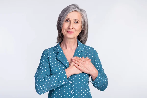 Foto de feliz sonriente pacífica hermosa mujer de negocios cogida de la mano pecho agradecido aislado sobre fondo de color gris —  Fotos de Stock