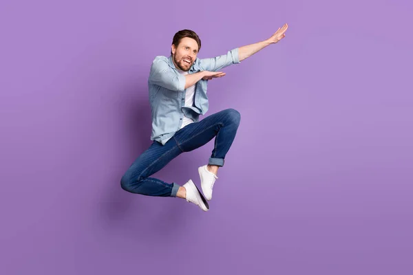 Foto de doce bonito jovem vestido camisa jeans saltando alto olhando espaço vazio isolado cor roxa fundo — Fotografia de Stock