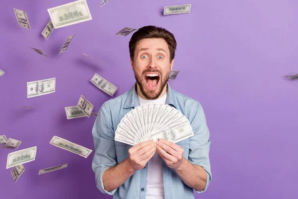 Fotografie bláznivý ohromený mladý muž křik šťastný loterie peníze izolované na fialové barvy pozadí — Stock fotografie