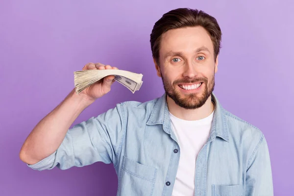 Photo of cheerful happy young man hold cash hand good mood smile loan deposit isolated on purple color background — Stock Photo, Image