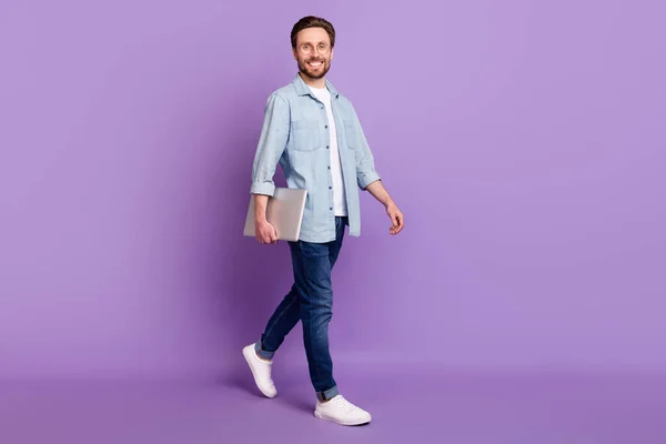 Plná velikost fotografie šťastný veselý usmívající se podnikatel jít procházka s notebookem v rukou izolovaných na fialové barvy pozadí — Stock fotografie
