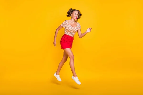 Full längd profil foto av dam hoppa springa slitage randig t-shirt mini kjol skor isolerad gul färg bakgrund — Stockfoto