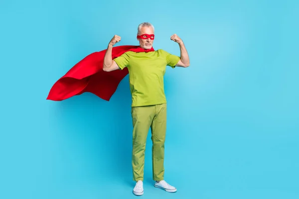 Tamanho do corpo de comprimento total vista de belo super-homem de cabelos grisalhos demonstrando braços poderosos isolados sobre fundo de cor azul brilhante — Fotografia de Stock