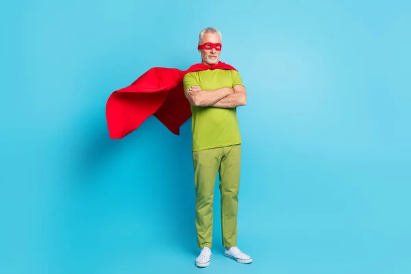 Volledige lichaamsomvang uitzicht van aantrekkelijke grijs-harige superman gevouwen armen wind waait geïsoleerd over helder blauwe kleur achtergrond — Stockfoto