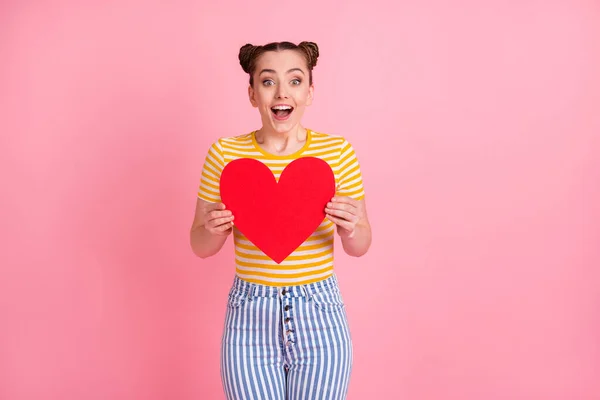 Foto de atraente espanto menina braços segurar papel coração símbolo cartão isolado no fundo cor-de-rosa — Fotografia de Stock