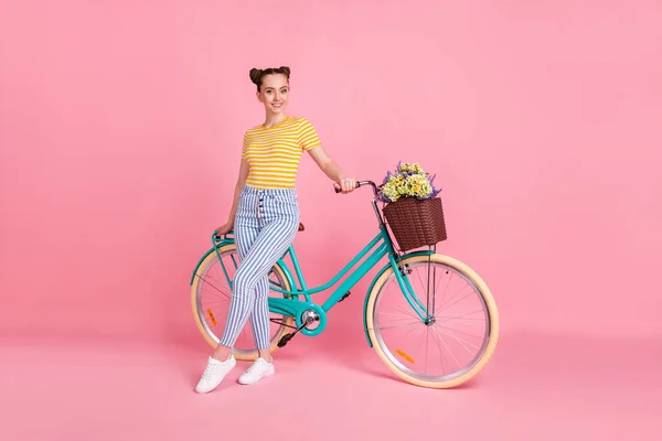 Foto de perfil em tamanho completo de otimista agradável morena senhora stand bicicleta desgaste amarelo t-shirt calças tênis isolado no fundo cor-de-rosa — Fotografia de Stock
